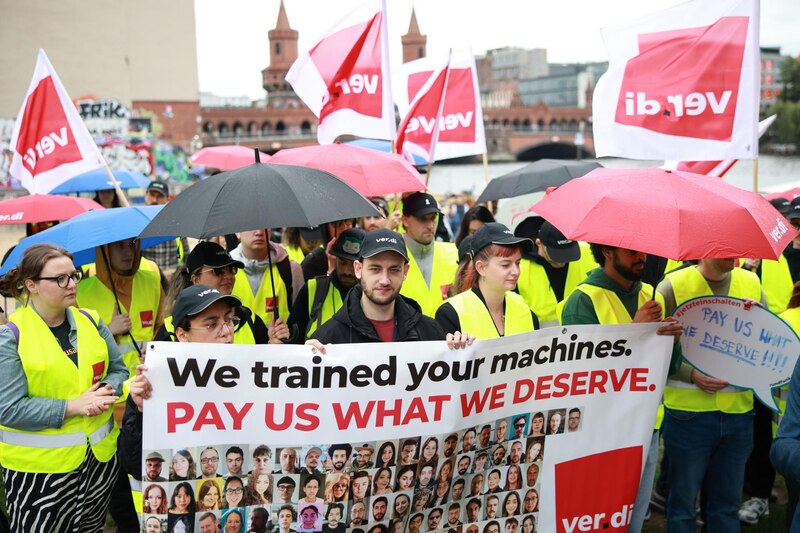 Vista frontal de manifestantes en huelga frente al edificio de TikTok Berlín con carteles sindicales