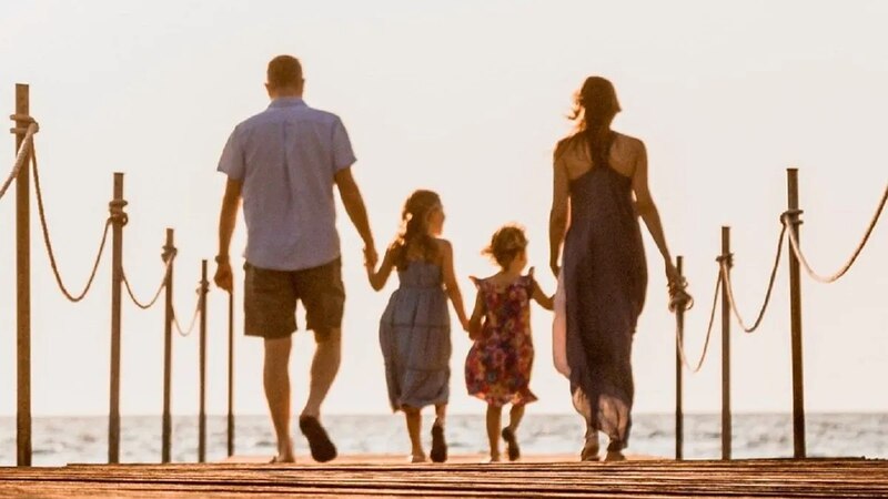 Familia feliz caminando por un muelle al atardecer