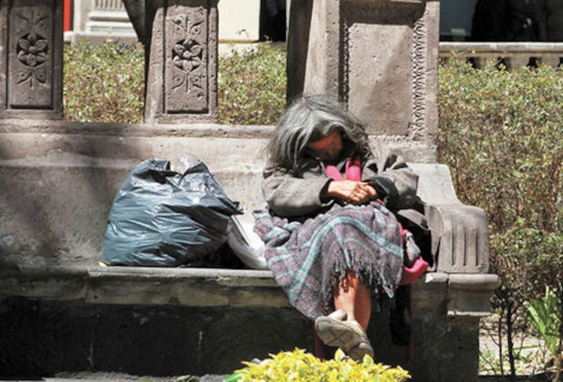 Mujer indigente duerme en una banca
