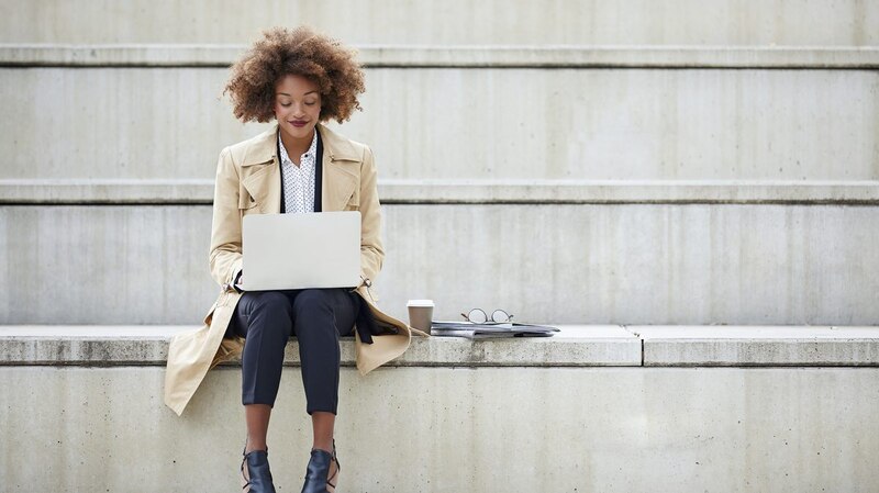 Mujer joven usando laptop en la ciudad