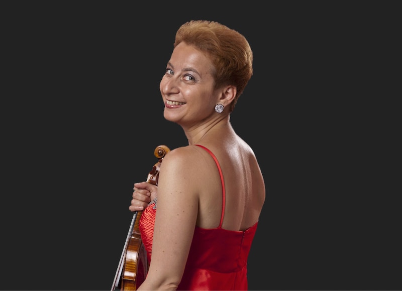 La violinista Leticia Moreno sonríe mientras sostiene su violín.