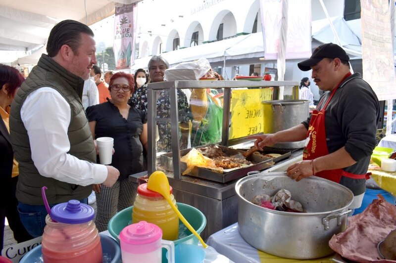 Un hombre prepara comida en un puesto de comida en la calle.