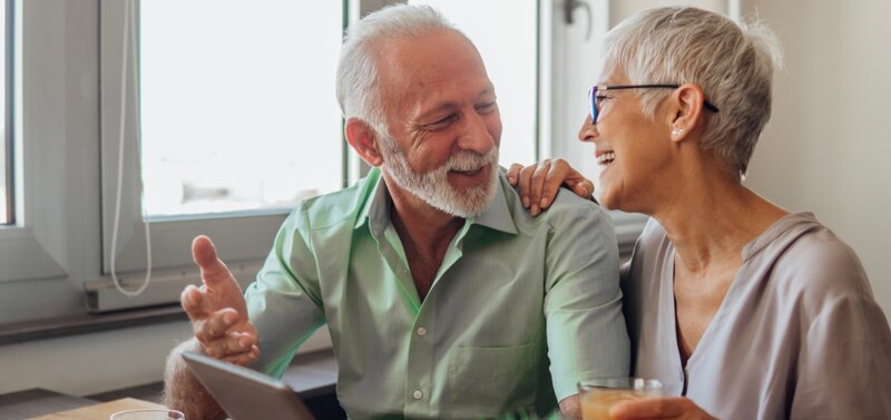 Pareja de ancianos sonríe mientras mira una tableta