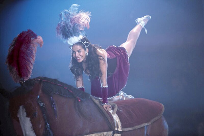 Mujer realizando acrobacia sobre un caballo en un circo