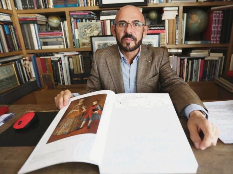 El historiador mexicano Pedro Salmerón lee un libro antiguo en una biblioteca.