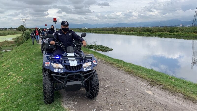 Policía en cuatrimoto patrulla un canal de agua