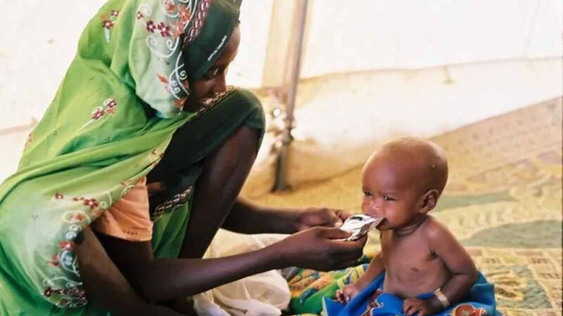 Madre dando de comer a su bebé en un campo de refugiados