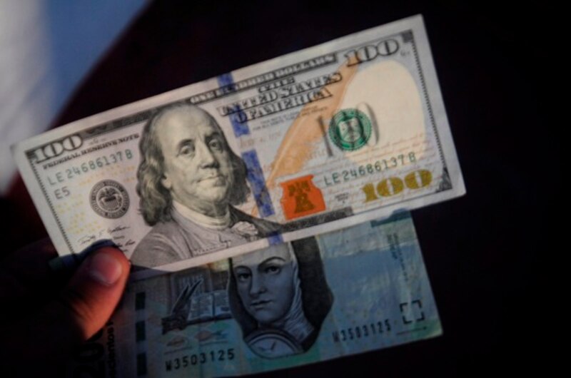 Imagen de un billete de 100 dólares y un billete de 100 pesos colombianos