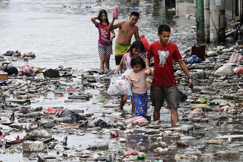 Un grupo de niños camina por las calles inundadas de Manila, Filipinas este lunes tras el paso del tifón Fung-Wong