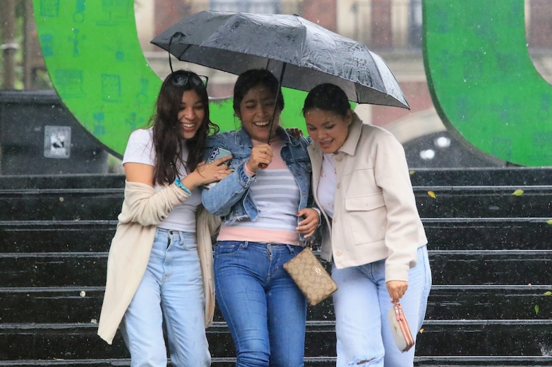 Tres mujeres se ríen bajo la lluvia