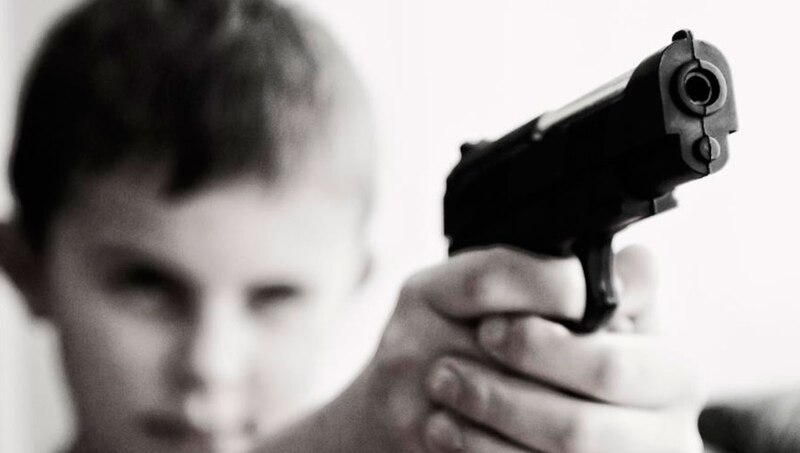 Niño apunta con una pistola