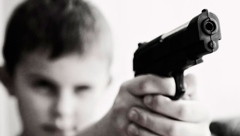Niño apunta con una pistola