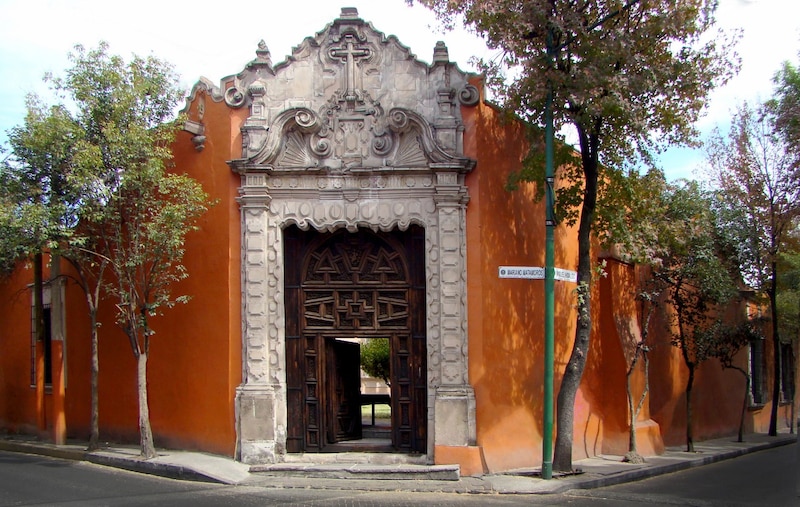 Puerta de madera tallada en una pared naranja