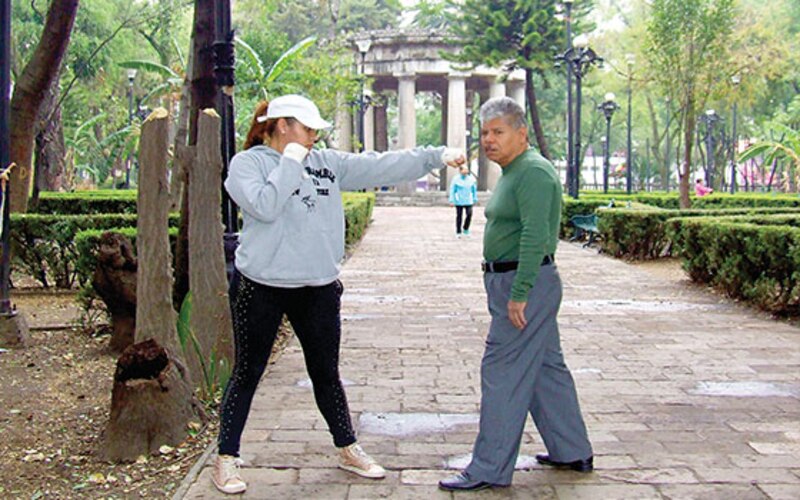 Mujer boxeadora golpea a hombre en el parque