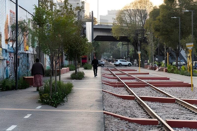 Una mujer camina por una vía férrea en desuso.