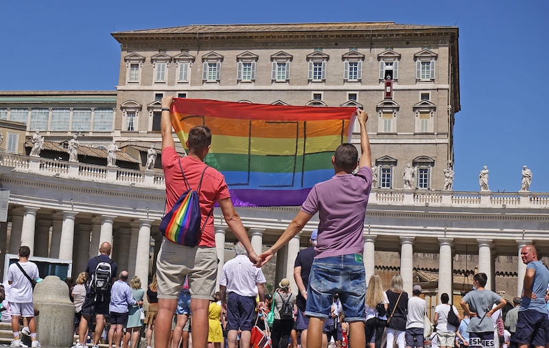 Pareja gay ondeando la bandera LGTBI en la Plaza de San Pedro