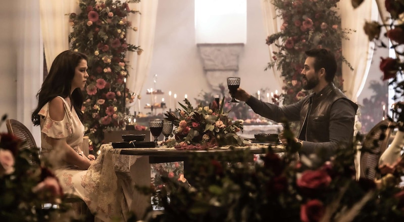 La pareja se sienta en una mesa decorada con flores y se miran con tristeza.