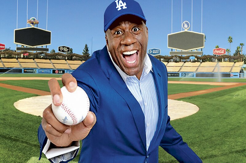 El exjugador de béisbol y comentarista deportivo, Magic Johnson, lanza una pelota de béisbol en un estadio de béisbol.