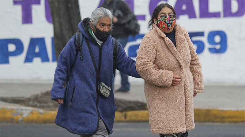 Dos mujeres caminan por la calle con mascarillas puestas