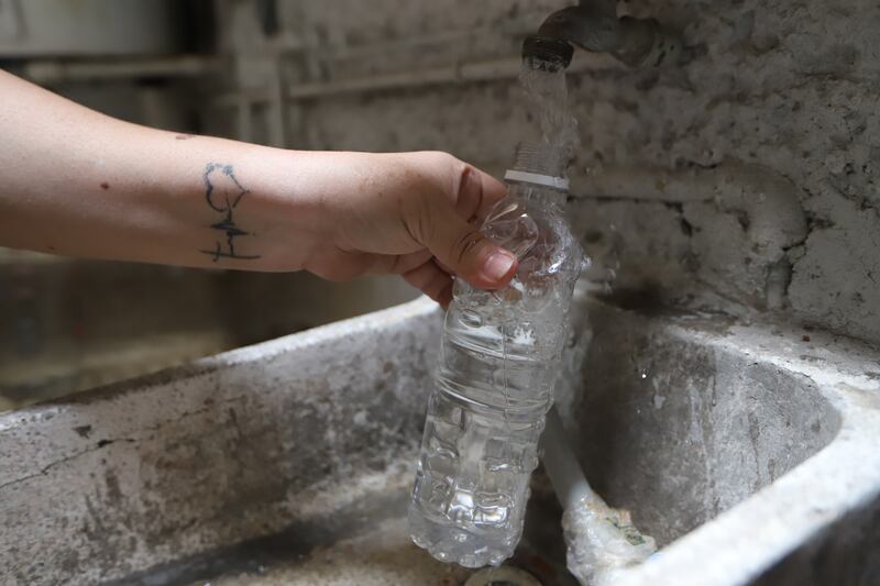 Mujer llenando una botella de agua en un lavabo