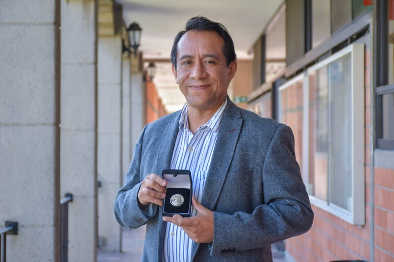 Profesor muestra con orgullo su medalla