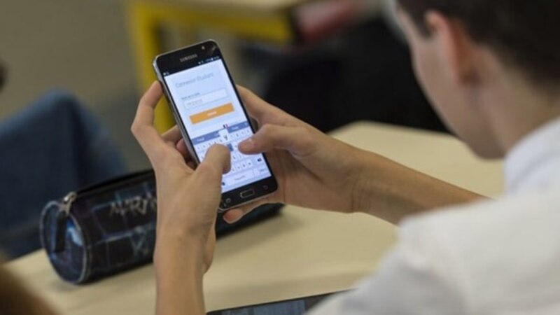 Un estudiante usando su teléfono móvil en clase