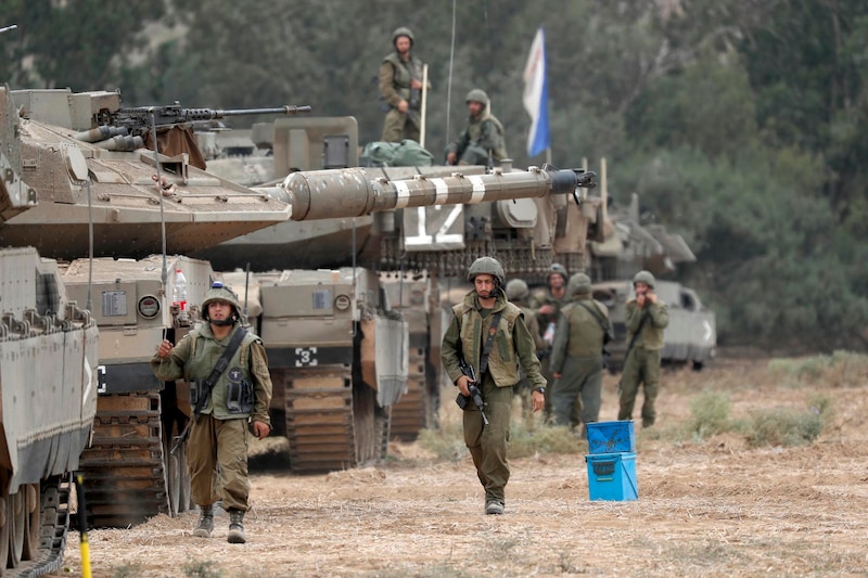 Soldados israelíes caminan junto a tanques Merkava