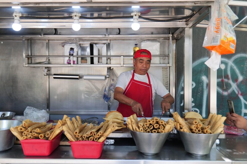 Un hombre preparando tacos en un puesto callejero