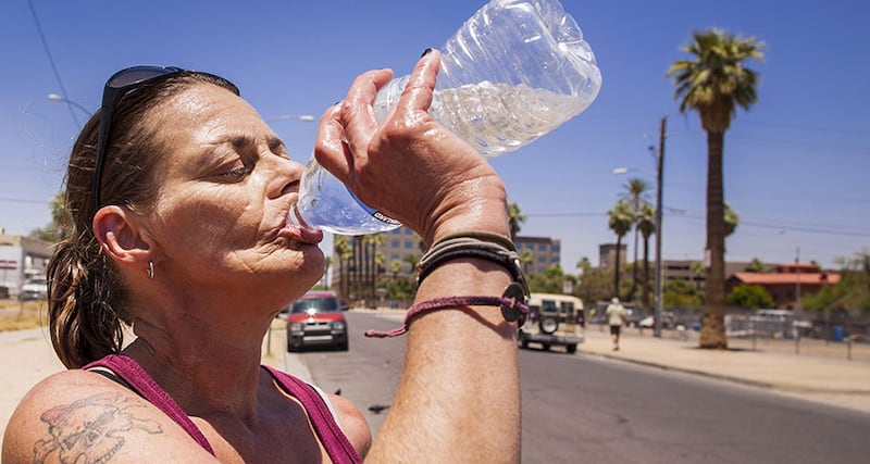 Mujer bebiendo agua en una botella de plástico