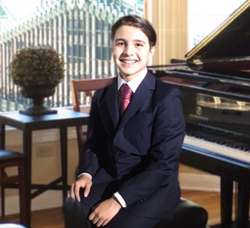 Joven pianista sentado junto a un piano de cola