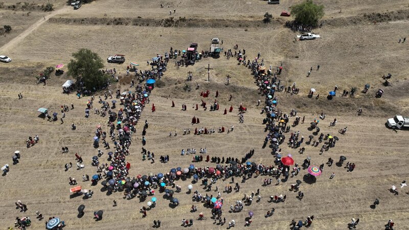 Multitud de personas reunidas en forma de cruz en un campo abierto