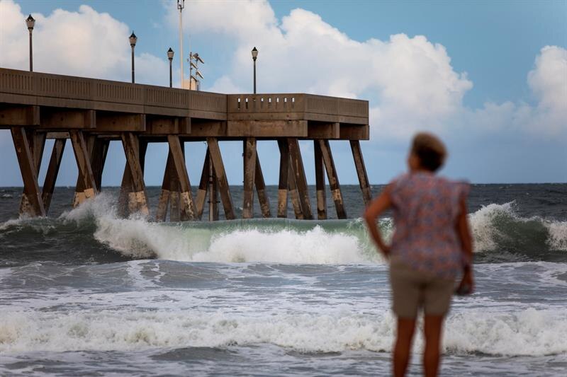 Mujer mirando las olas del mar desde un muelle