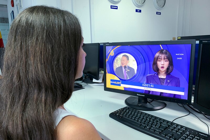 Una mujer joven mira las noticias en una pantalla de ordenador.