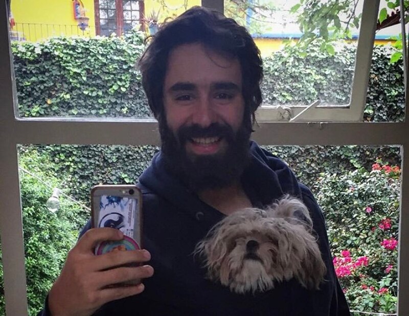 Un hombre con barba y una mascota en una mochila