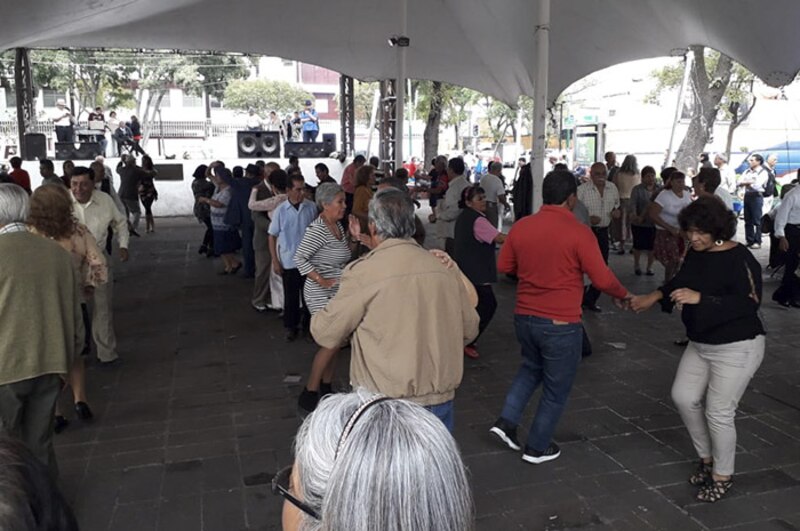 Personas mayores bailando en una plaza pública