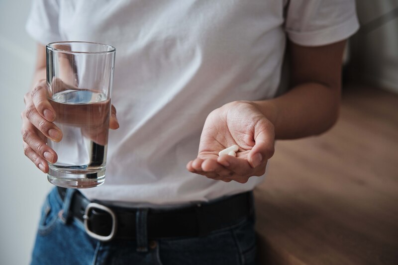 Mujer tomando una pastilla con un vaso de agua