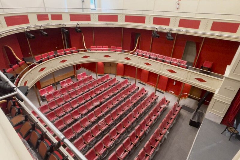 Un teatro vacío con filas de asientos rojos