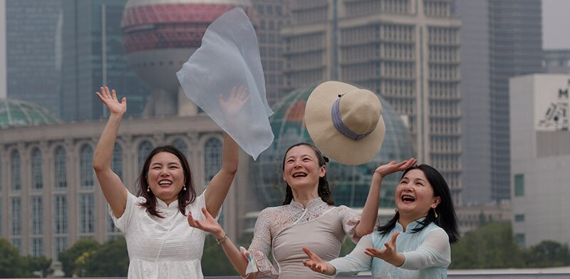 Tres mujeres chinas se ríen y ondean telas en el aire