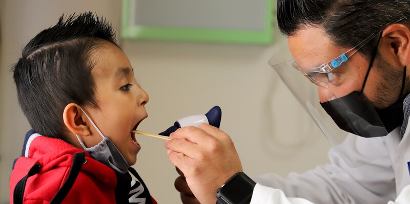 Doctor examinando la garganta de un niño