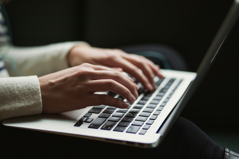 Mujer escribiendo en un teclado de ordenador portátil