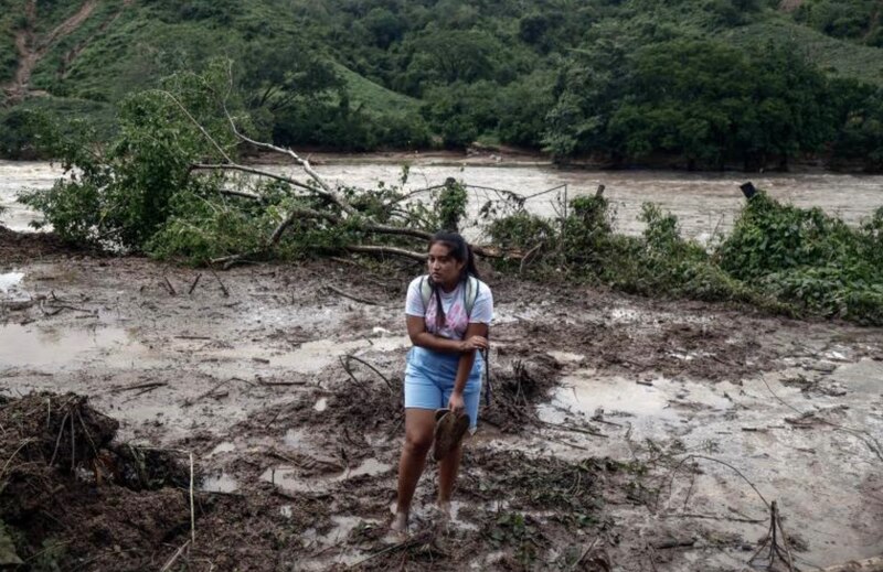 Mujer camina sobre el lodo tras una inundación