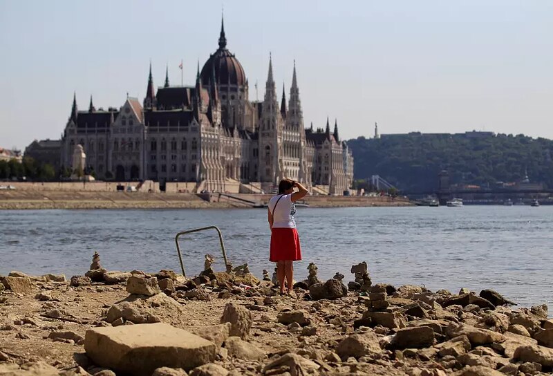 Mujer mirando al Parlamento Húngaro desde la orilla del río Danubio