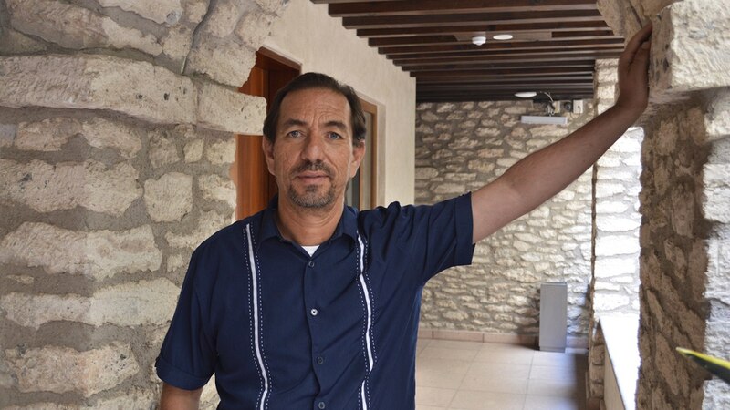 Un hombre apoyado en una columna de piedra