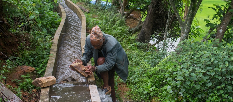 Un hombre arreglando un canal de agua en Nepal