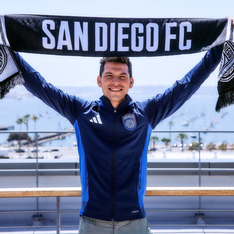 Jugador de fútbol con uniforme azul y blanco sostiene una bufanda del San Diego FC