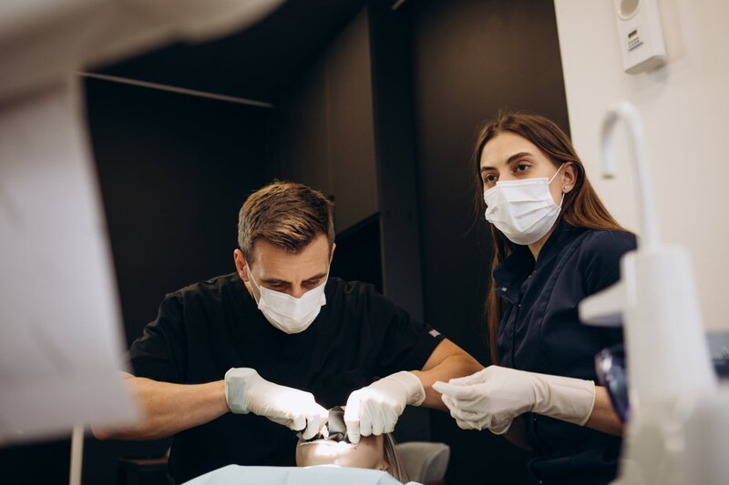 Dentista y paciente enmascarados durante un procedimiento dental