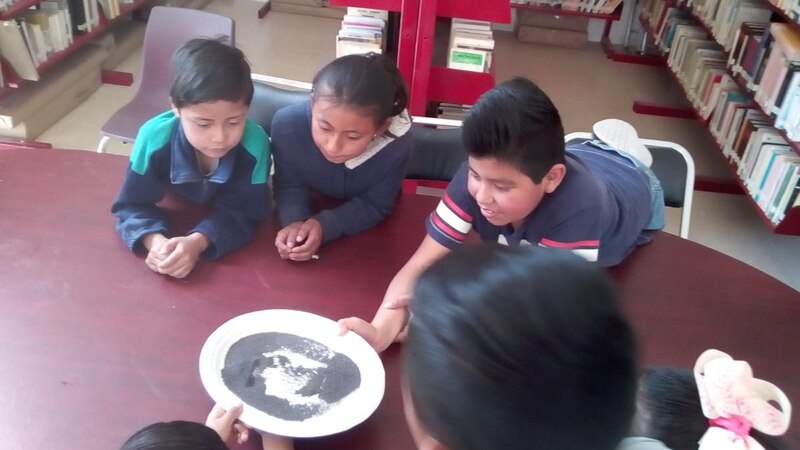 Niños jugando con arena en la biblioteca