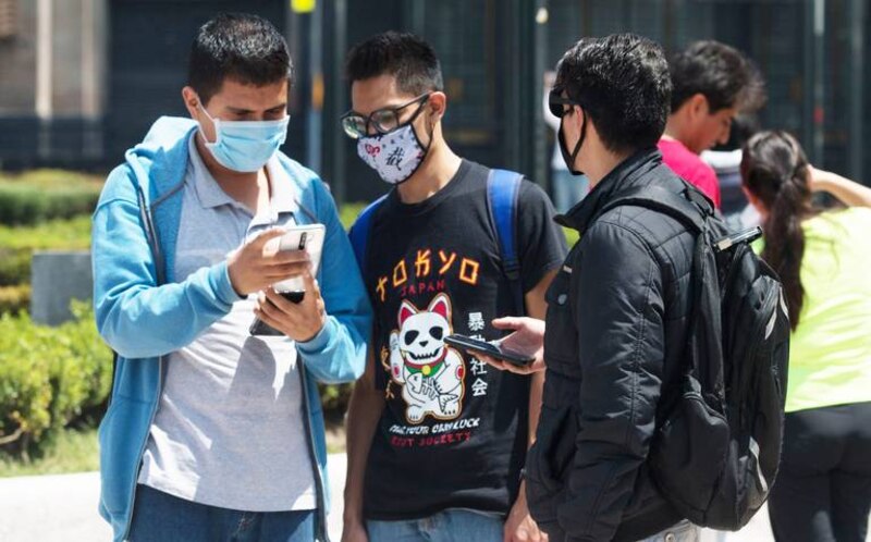 Jóvenes usando sus teléfonos móviles en la calle
