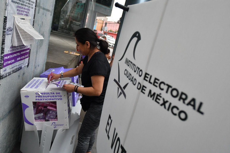 Mujer deposita su voto en una urna durante una consulta de presupuesto participativo en la Ciudad de México