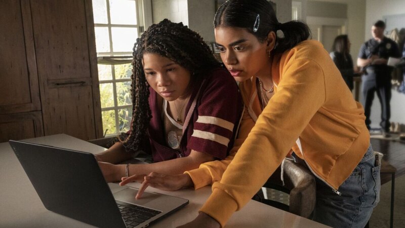 Dos chicas adolescentes están usando una computadora portátil en una cocina